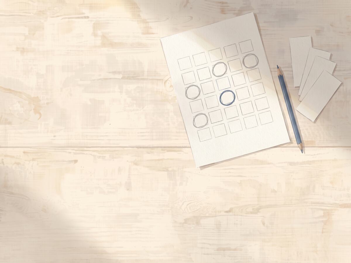 A hand-drawn grid of empty squares on paper with four dates ringed in pencil and one ringed in blue, and four blank slips fanned beside it.